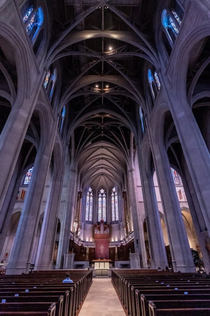 Dramatic view of a Gothic cathedral interior featuring towering columns and vibrant stained glass windows.