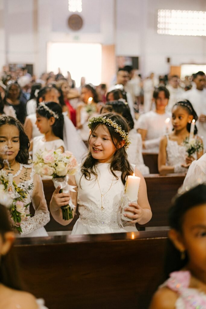 Young girls in white dresses participate in a beautiful First Communion ceremony at a church.