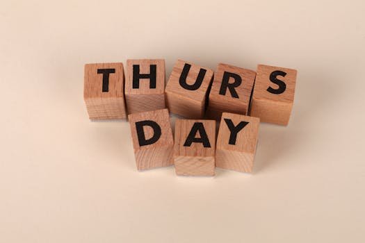 Wooden letter blocks arrange to spell 'Thursday' on a plain background, ideal for week or calendar themes.