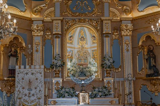 Ornate church altar with detailed gold accents and floral arrangements in Santa Pola, Spain.